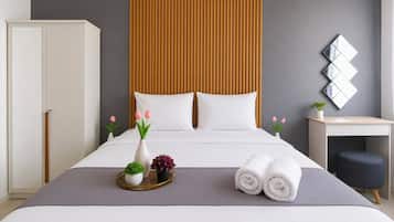 A modern hotel room with a bed, bedside table, and a desk with a chair.