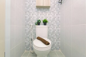 Ein Badezimmer mit Toilette, Dusche und gefliesten Wänden.
