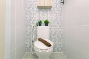 Une salle de bain avec des toilettes, une douche et un mur carrelé.