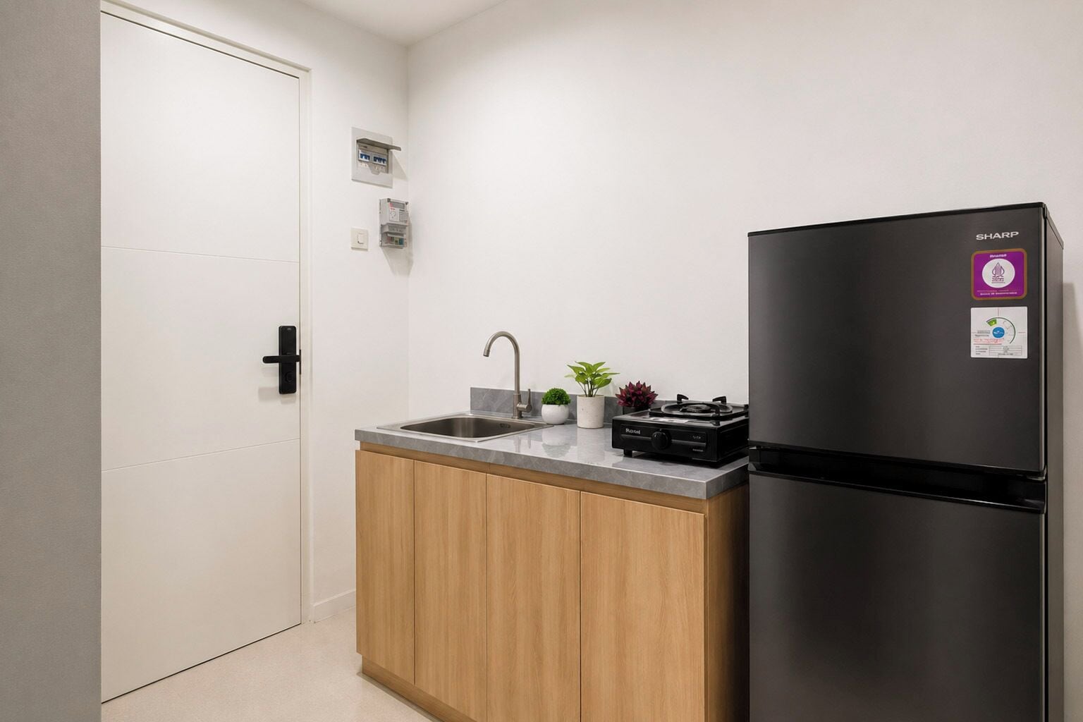A compact kitchen with a black refrigerator, a sink, and a small countertop.
