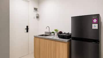 A compact kitchen with a black refrigerator, a sink, and a small countertop.