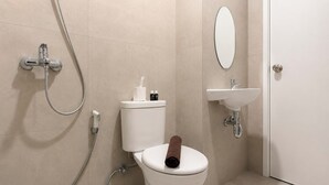 A bathroom with a toilet, a bidet, a shower, a sink, and a mirror. - Warm And Stylish 1Br At Apartment Kyo Society (Surabaya)