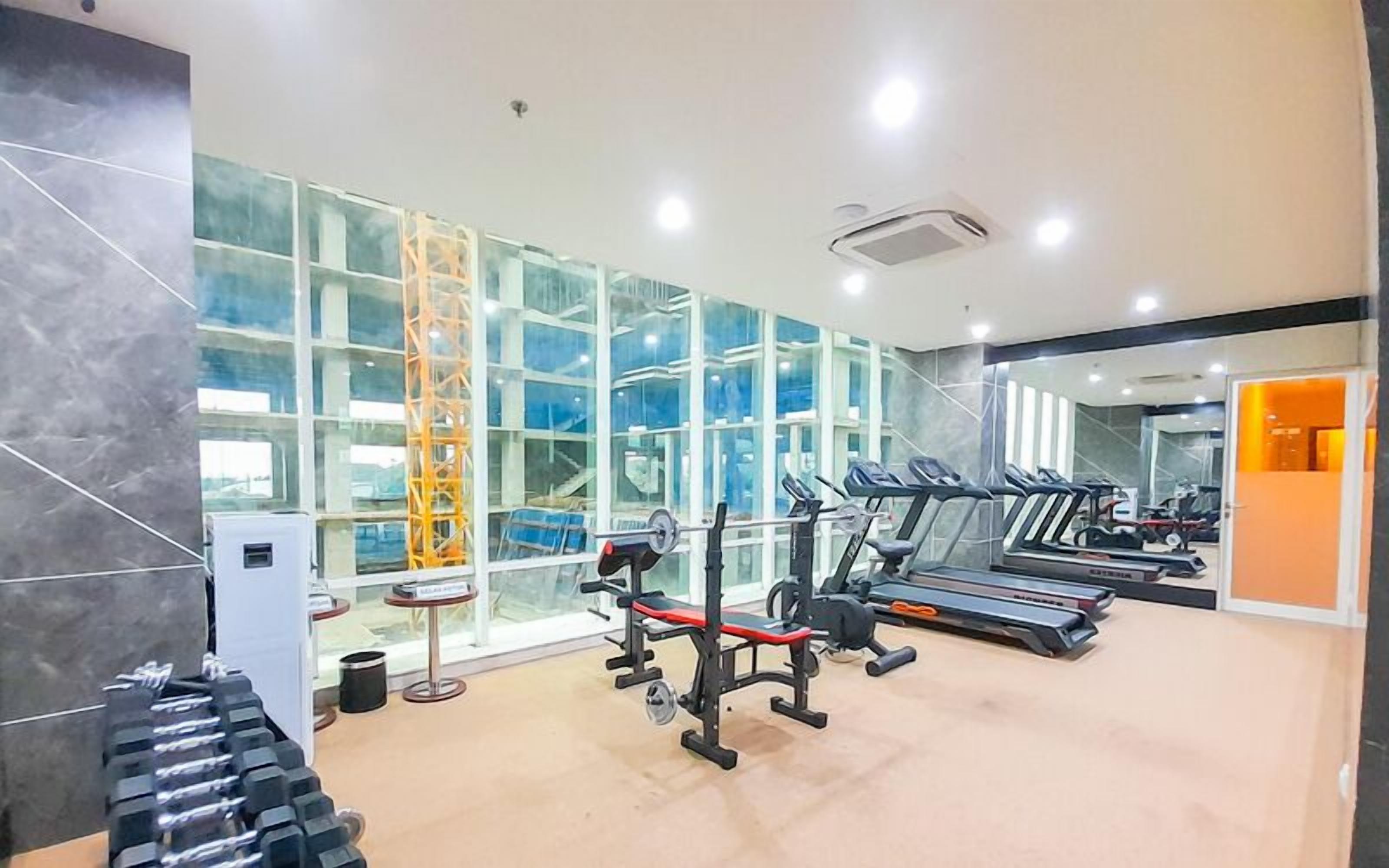 A gym with treadmills, weight machines, and dumbbells.