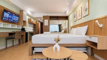 Una habitación de hotel moderna con cama, mesitas de noche, escritorio y televisor.