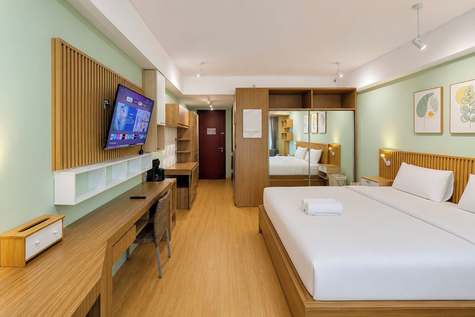 A hotel room with a bed, a desk, a television, and a wardrobe.