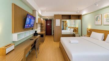 A hotel room with a bed, a desk, a television, and a wardrobe.