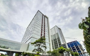 Two high-rise buildings with modern architecture, one with a glass facade and the other with a metal exterior. - Enjoyable Studio At Apartment Mataram City Palagan Yogyakarta (Ngaglik)