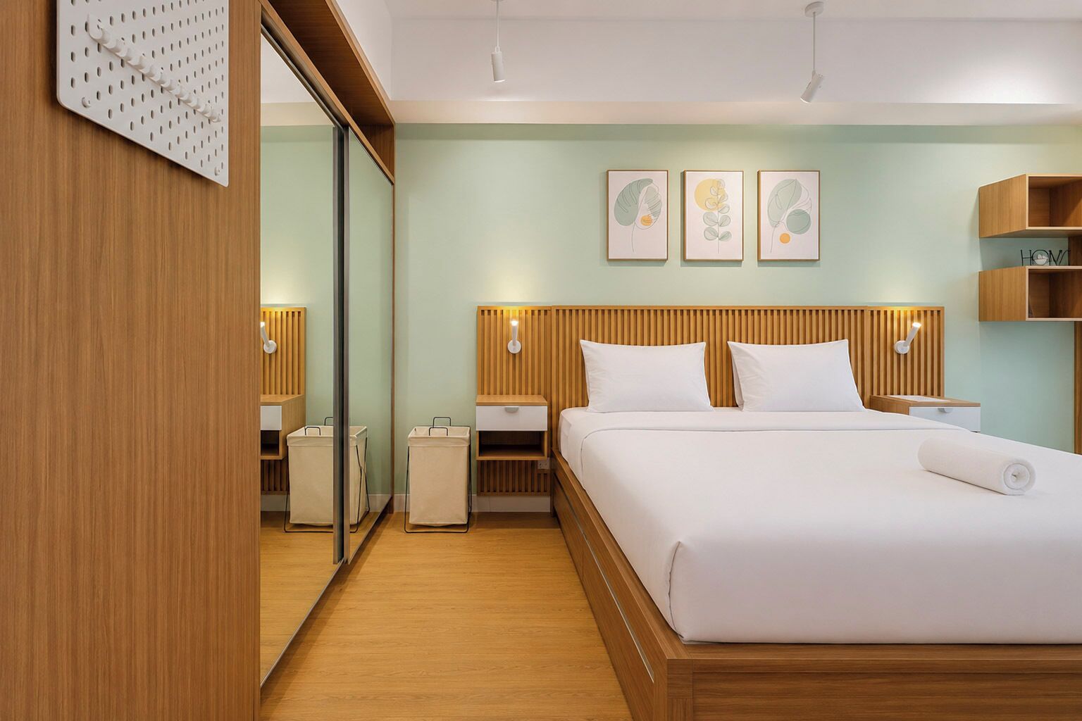 Una habitación de hotel con una cama grande, cabecera de madera, mesitas de noche, un espejo y obras de arte en la pared.