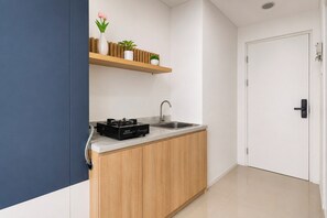 A modern kitchen with a built-in stove, sink, and wooden cabinets. - Stylish Bright 1Br At Apartment Kyo Society (Surabaya)