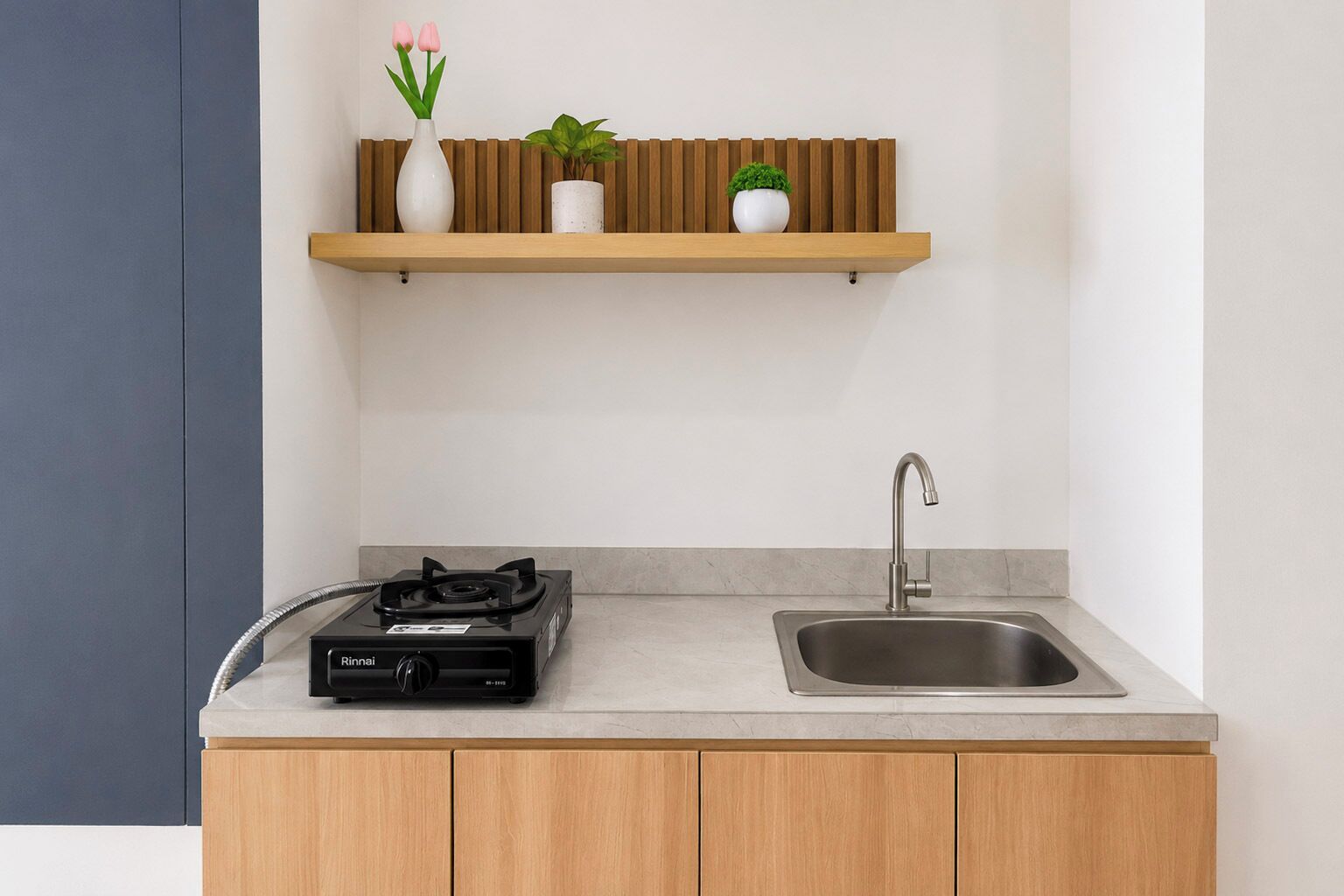 A modern kitchen with a gas stove, stainless steel sink, wooden cabinets, and a floating shelf with potted plants.
