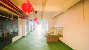 A corridor with a green floor, a display case on the right, and red hanging decorations. - Relaxing Studio At Apartment Skyview Medan (Medan)