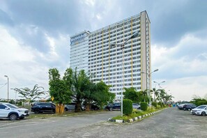 A multi-story hotel with a modern design, featuring a prominent entrance and a parking area with cars. - Relaxing Studio At Apartment Skyview Medan (Medan)