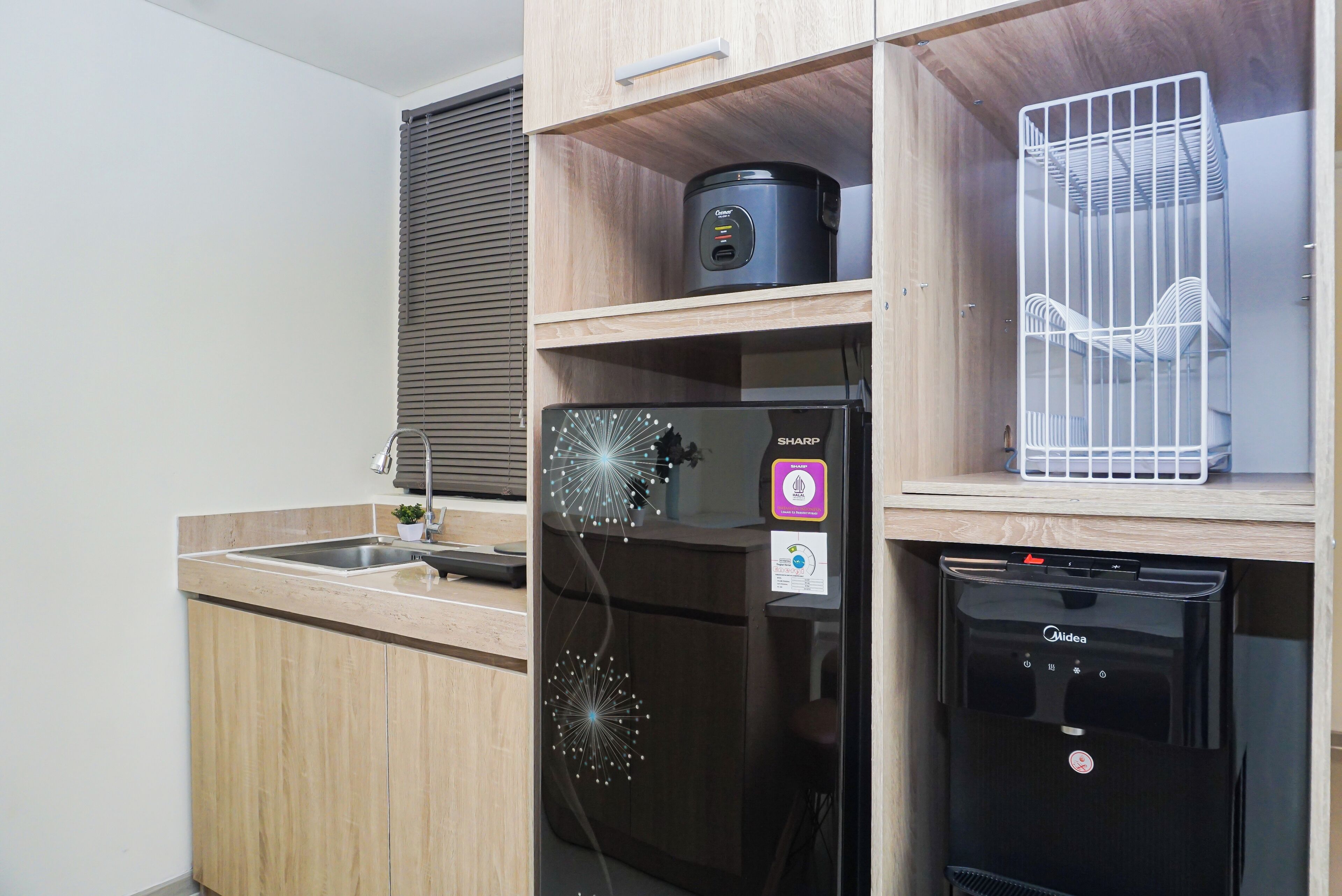 Una cocina compacta con cafetera integrada, un refrigerador con el logotipo Sharp y un lavavajillas.