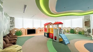 A play area with a slide and climbing structures, a sofa, and a television. - Elegant Studio At Apartment Antasari Place (Jakarta)
