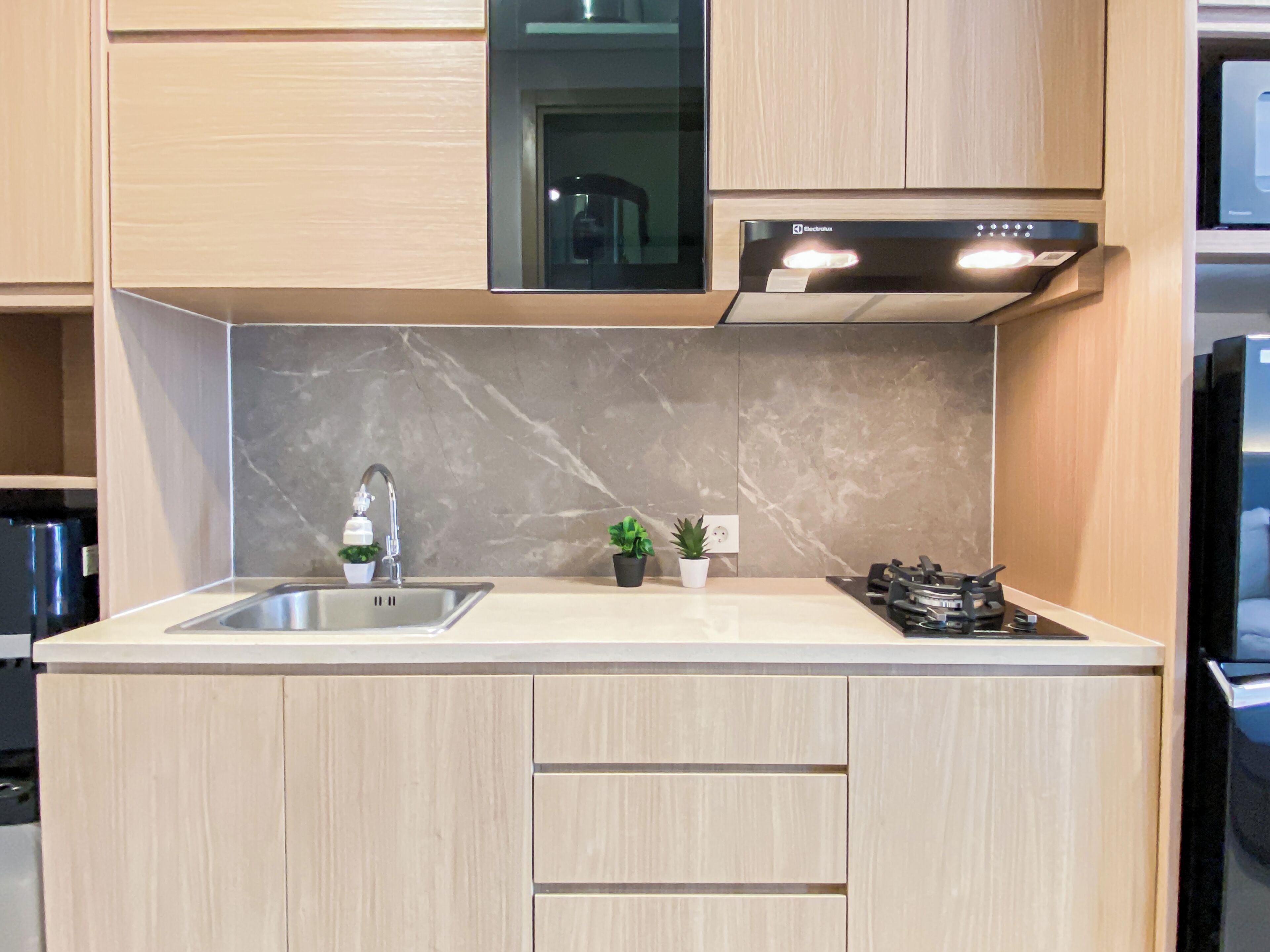 A modern kitchen with a stainless steel sink, a built-in stove, and wooden cabinets.