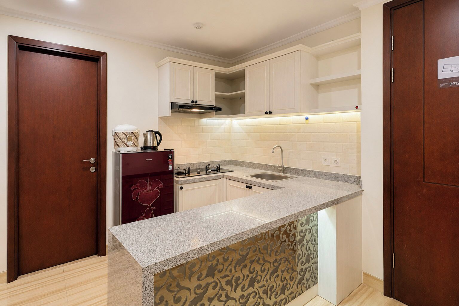 Una cocina compacta con estufa integrada, un lavabo y armarios superiores.