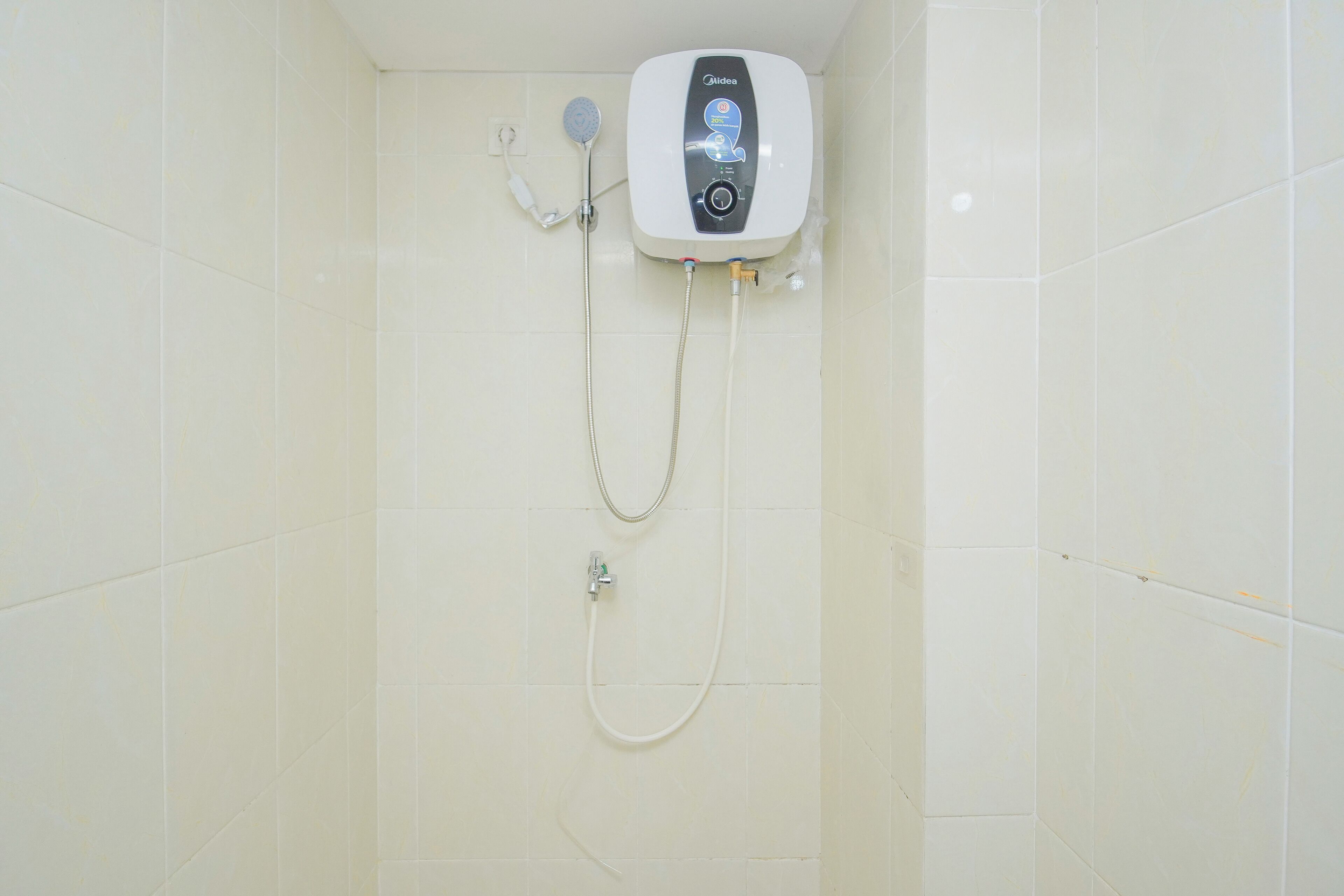 Una ducha con panel de control y cabezal de ducha manual, instalada en una pared con azulejos.