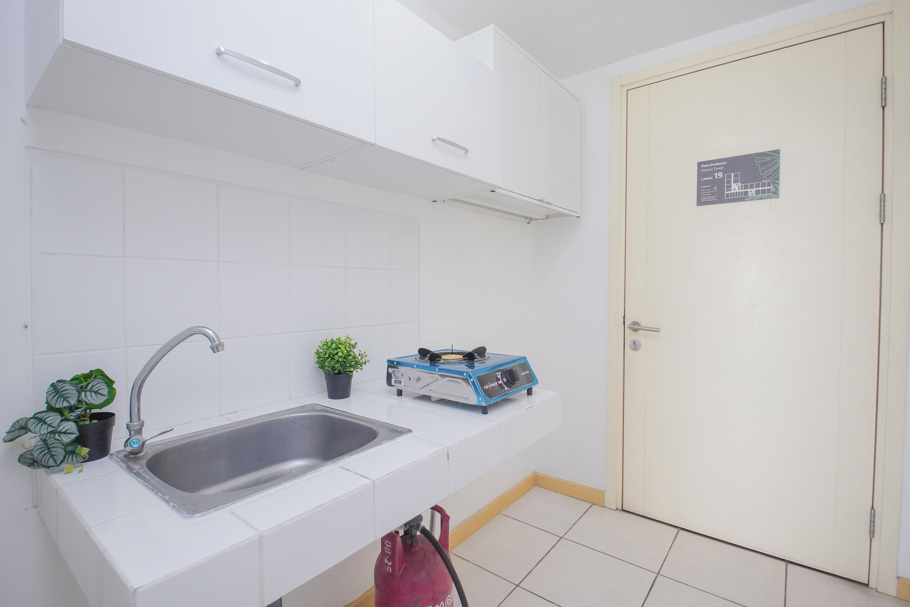 Una cocina con un lavamanos, una planta en maceta y un electrodoméstico azul en la encimera.