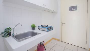 Una cocina con un lavamanos, una planta en maceta y un electrodoméstico azul en la encimera.