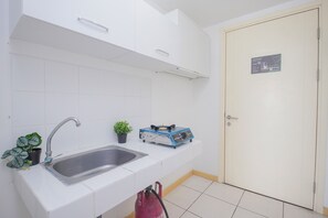 Una cocina con un lavamanos, una planta en maceta y un electrodoméstico azul en la encimera.