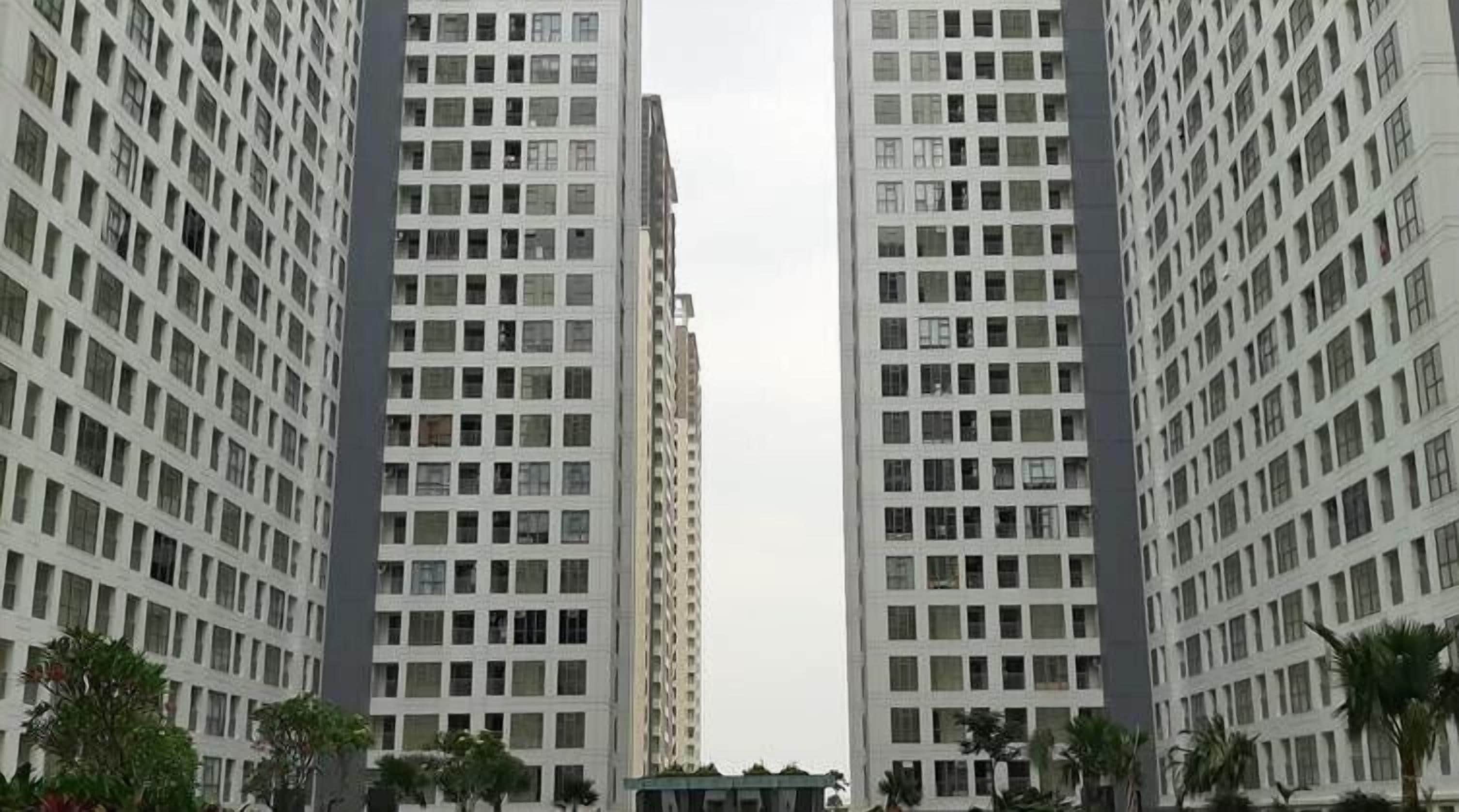 Un edificio de gran altura con fachada enrejada, varios pisos y un patio central con árboles.