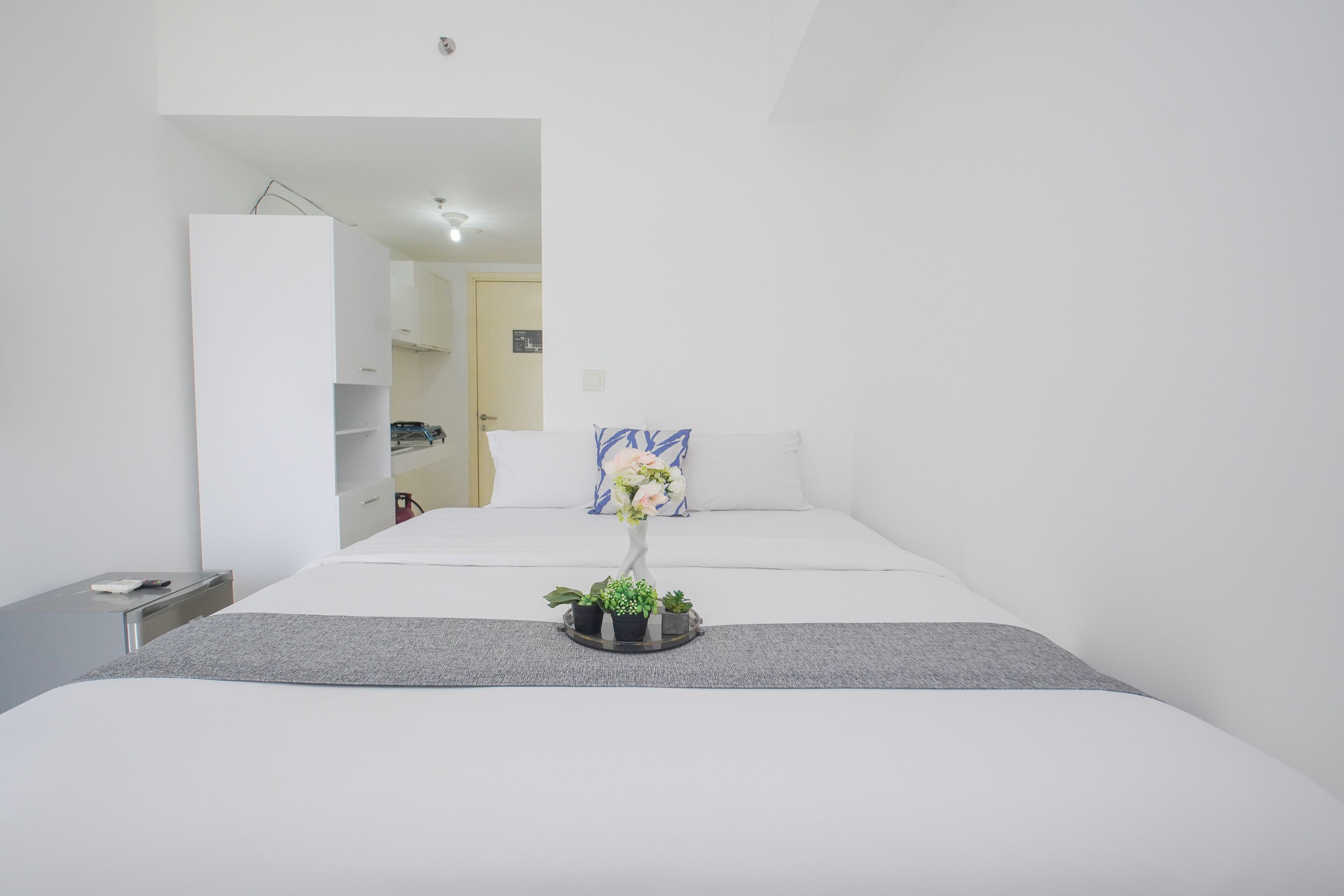 A modern hotel room with a large bed, a small bedside table, a nightstand, and a dresser.