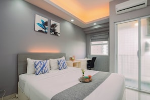 A modern hotel room with a large bed, a desk, and a window. - Elegant Cozy Living Studio At Apartment Parkland Avenue (Tangerang)