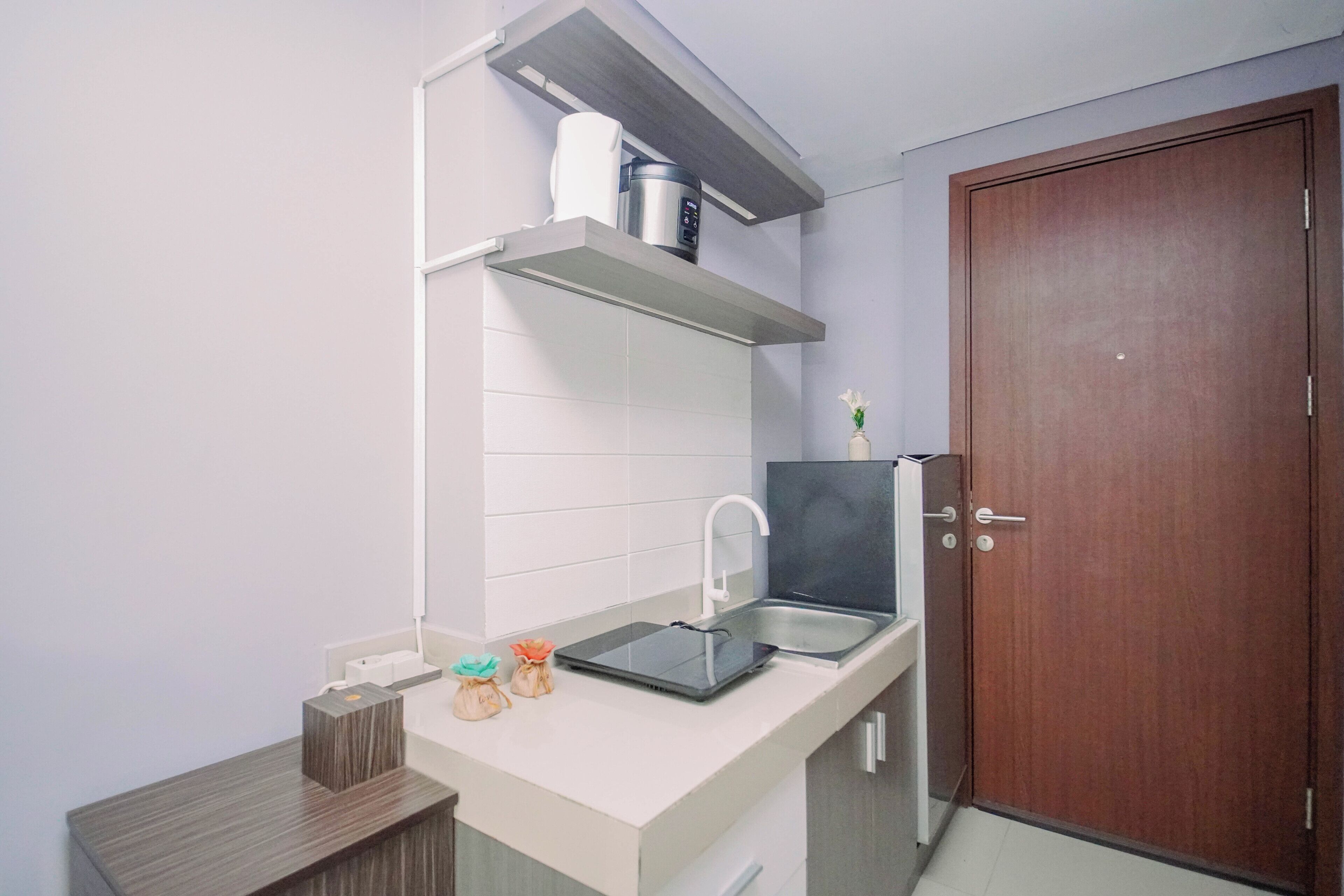 A compact kitchen with a built-in sink, a coffee maker, and a small countertop with a vase.
