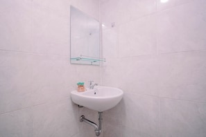 A bathroom with a white sink, a mirror, and a small plant on the counter. - Elegant Cozy Living Studio At Apartment Parkland Avenue (Tangerang)