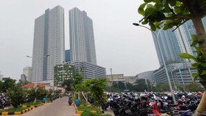 Paesaggio urbano con palazzi alti, un gran numero di motociclette parcheggiate e cielo sereno.