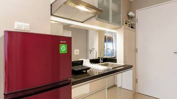 A compact kitchen with a red refrigerator, a built-in sink, and a stainless steel range hood.