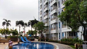 Un edificio residenziale con balconi, una piscina e un'area giochi per bambini.