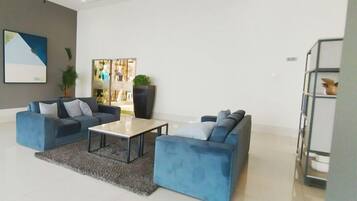 A modern living room with two sofas, a coffee table, and a large potted plant.