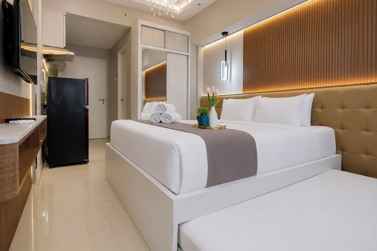 A modern hotel room with a bed, bedside table, and a built-in TV.