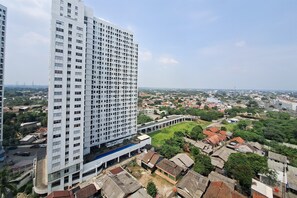 A high-rise building with a grid of windows, surrounded by a mix of residential and commercial buildings. - Nice And Tidy Studio Room At Apartment Cisauk Point (Cisauk)