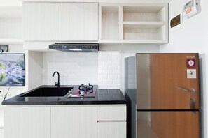 Una cocina con gabinetes blancos, encimera negra, refrigerador de acero inoxidable y estufa a gas.