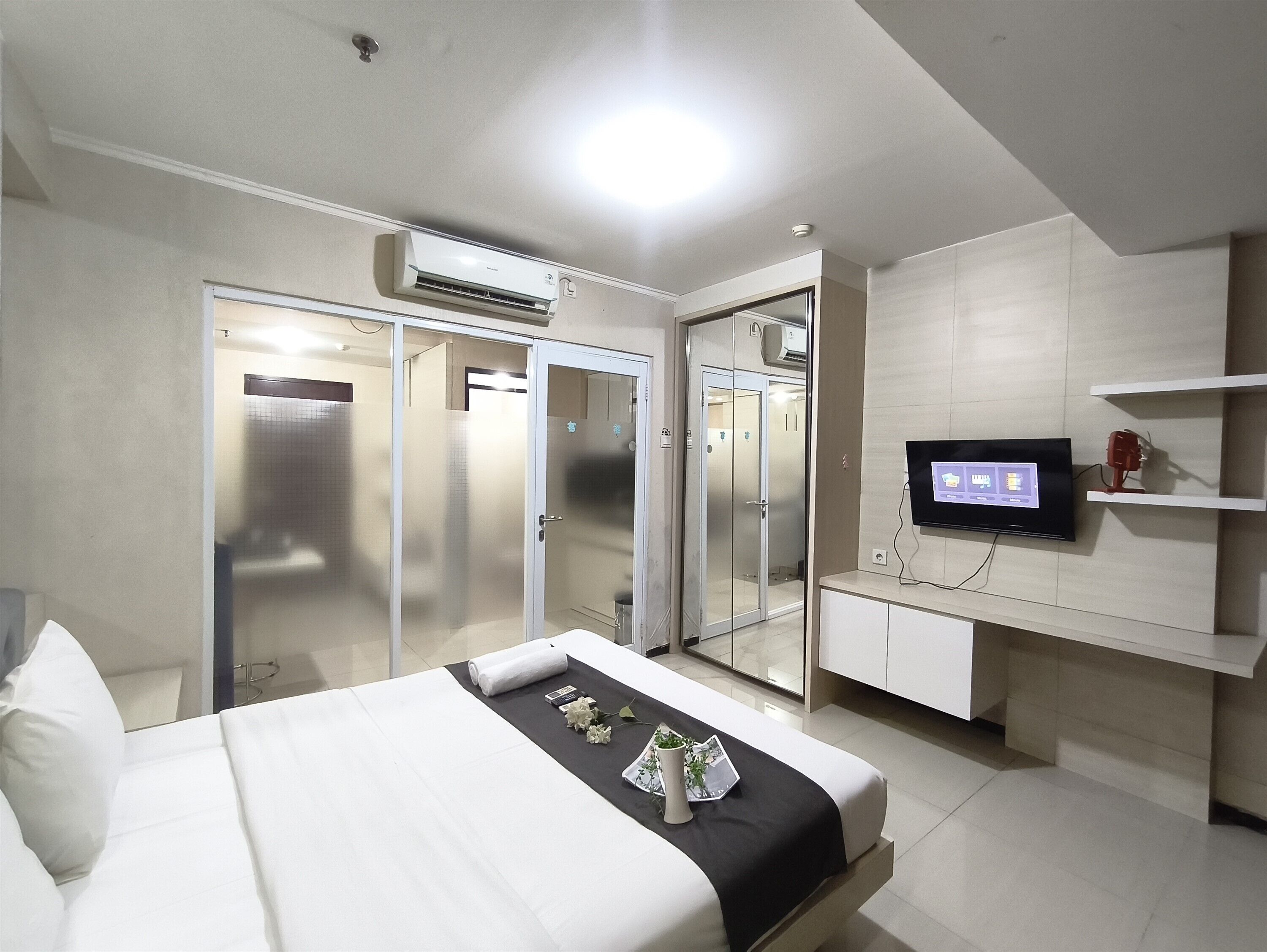 Ein Hotelzimmer mit Bett, Fernseher, Schreibtisch und Kleiderschrank.