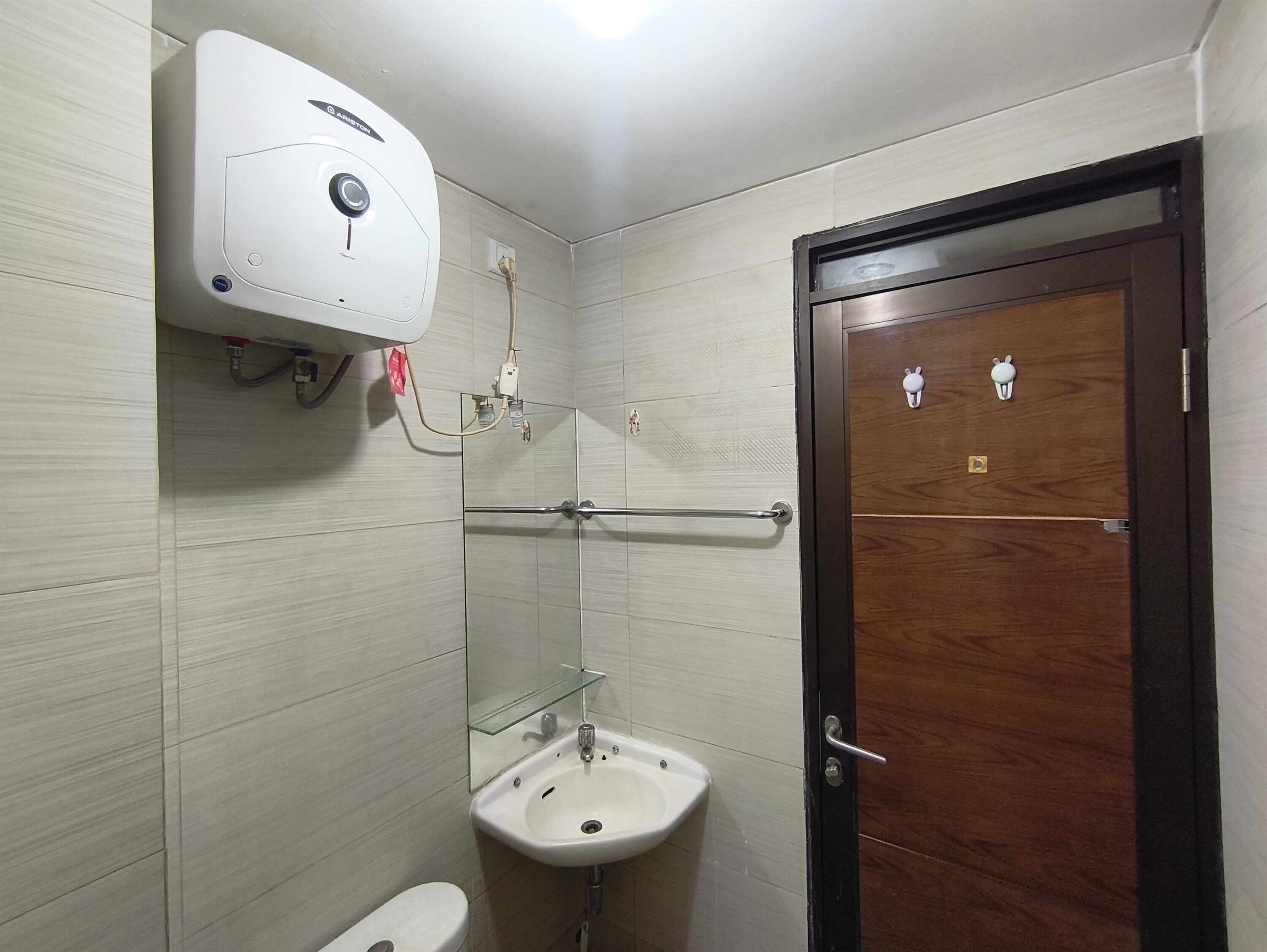 Un bagno con il water, un lavandino, uno specchio e una doccetta.