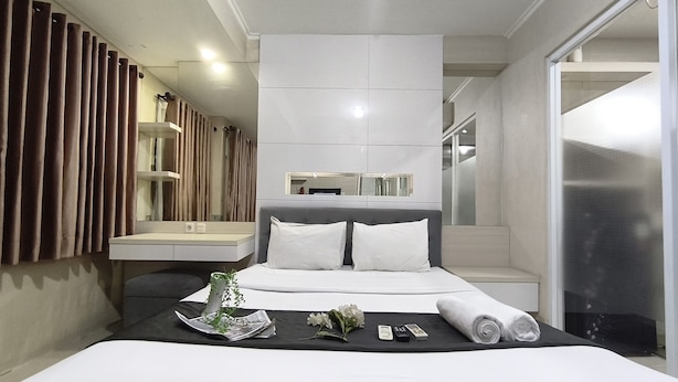 Ein Hotelzimmer mit einem großen Bett, einem Nachttisch, einem Spiegel und Blick ins Badezimmer.