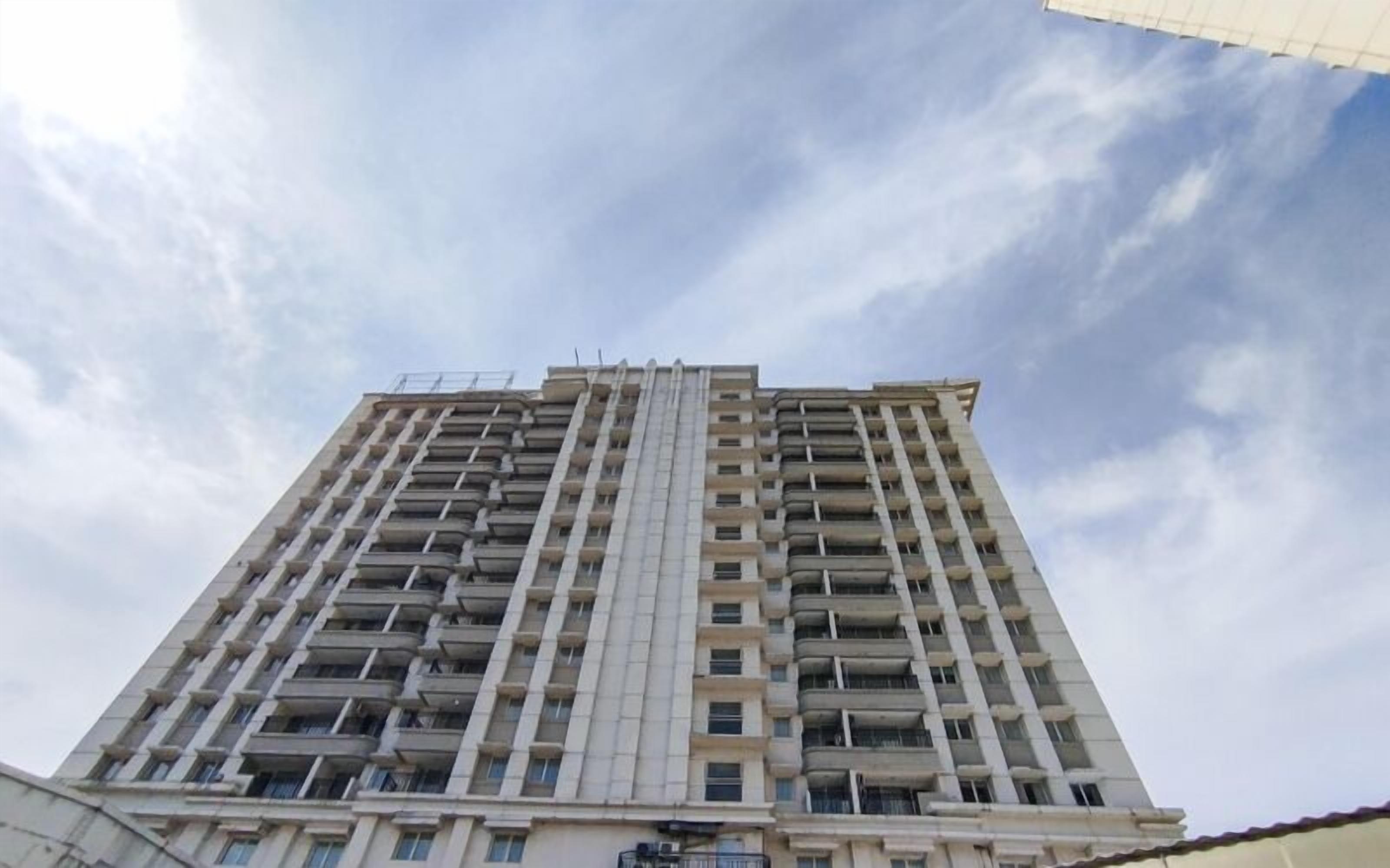 Un edificio alto con varios pisos, balcones y cielo despejado.
