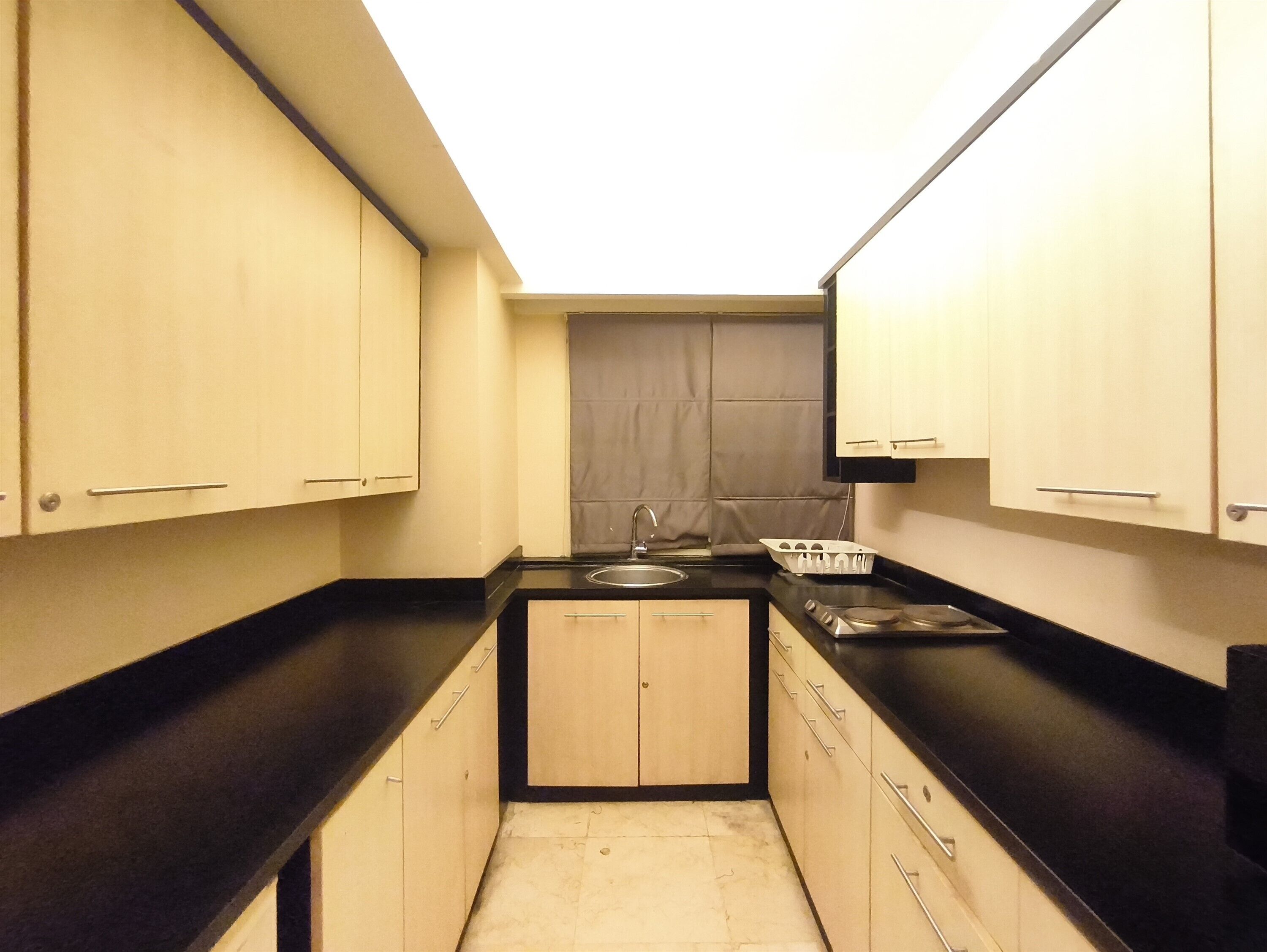 Una cocina compacta con lavamanos, estufa y armarios.