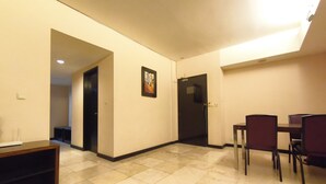 A hotel room with a dining area, a door, and a tiled floor. - Best Deal 3Br Apartment Braga City Walk (Bandung)