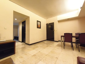 A hotel room with a dining area, a door, and a tiled floor. - Best Deal 3Br Apartment Braga City Walk (Bandung)