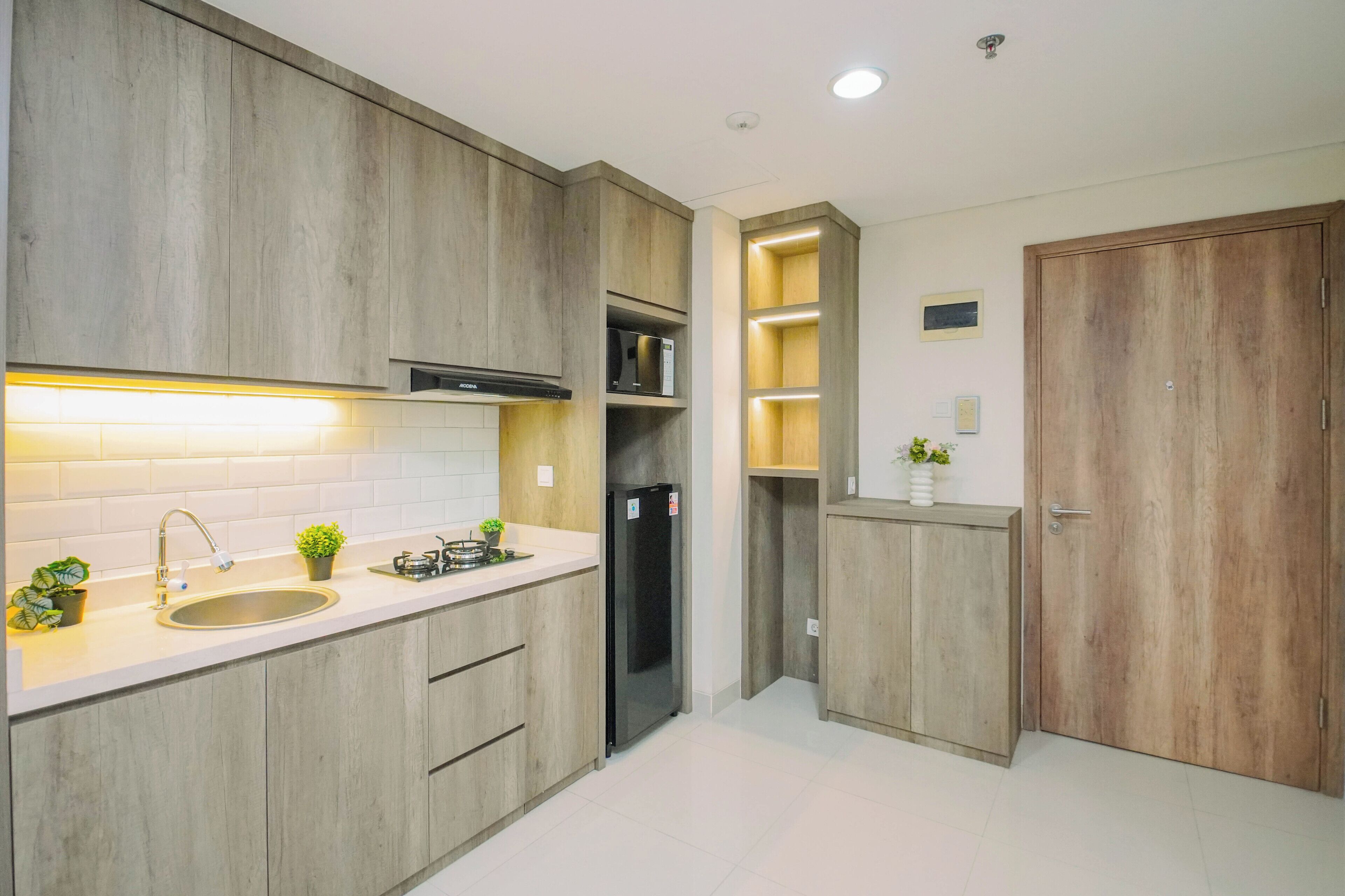A modern kitchen with wooden cabinets, a stainless steel sink, a black refrigerator, and a built-in microwave.