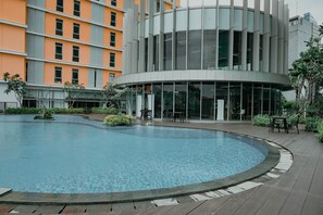 A modern building with a circular pool, outdoor seating, and a glass facade. - Smart Value 2Br At Apartment Pejaten Park Residence (Jakarta)