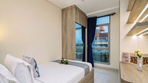 Ein modernes Schlafzimmer mit Bett, Nachttischen, einem Fenster mit Vorhängen und Blick auf Gebäude.