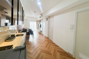 A modern kitchen with a built-in stove, a dining area with chairs, and a large window providing natural light. - Great Value 2Br At Apartment Podomoro City Deli Medan (Medan)