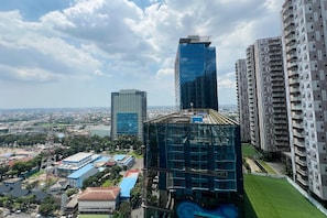 A high-rise building with a modern glass facade, surrounded by other high-rise buildings and a cityscape in the background. - Great Value 2Br At Apartment Podomoro City Deli Medan (Medan)