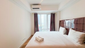 A hotel room with a large bed, a window with curtains, and an air conditioning unit on the wall. - Great Value 2Br At Apartment Podomoro City Deli Medan (Medan)