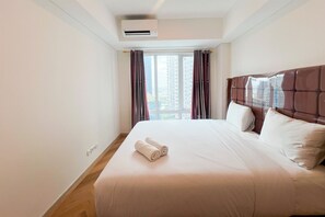 A hotel room with a large bed, a window with curtains, and an air conditioning unit on the wall. - Great Value 2Br At Apartment Podomoro City Deli Medan (Medan)